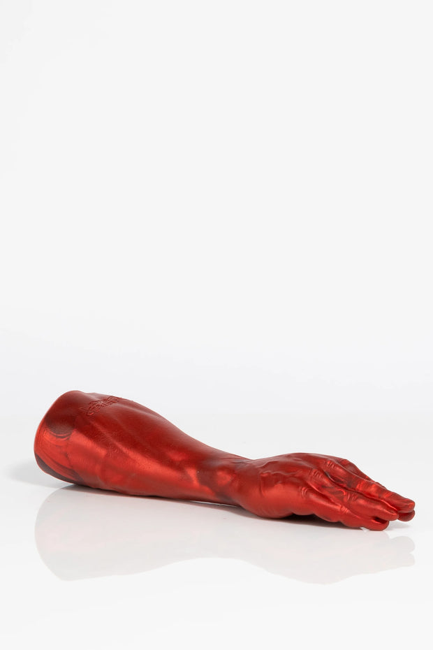 A product photo of a red fist dildo lying down.