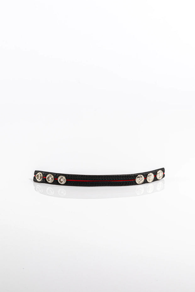 A product photo of a black pentagram-studded cock ring with a red trim.
