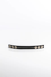 A product photo of a black pentagram-studded cock ring with white trim.
