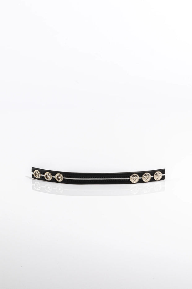 A product photo of a black pentagram-studded cock ring with white trim.